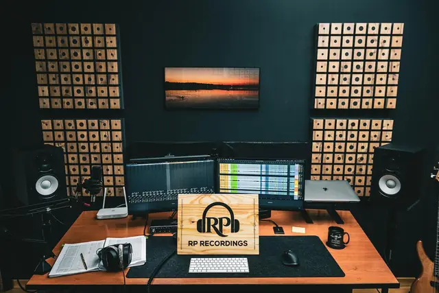 Estúdio da RP Recordings, com colunas, painéis de madeira e a placa pirogravada