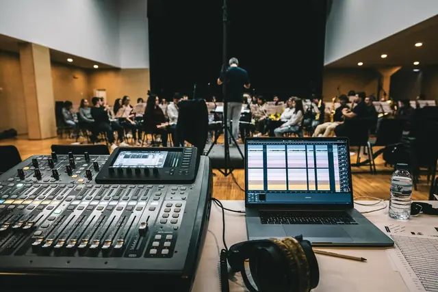 Mesa de mistura digital e portátil com a banda a ensaiar ao fundo